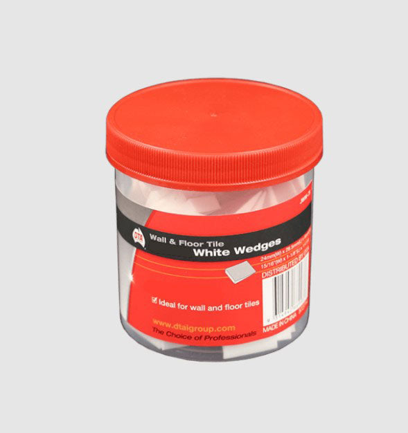 A clear plastic jar with red lid containing white wedge spacers for wall and floor tile installation.